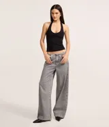 Pantalón de jean gris de tiro bajo y corte amplio, sin pretina, con cierre tradicional y bolsillos.
