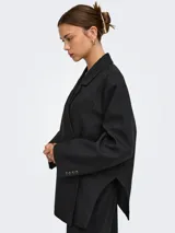 Blazer oversize color negro, con solapa clásica, bolsillos con ribete y diseño amplio de manga larga.