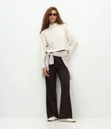 Suéter de cuello alto con diseño de punto texturizado y mangas largas. Presenta un corte holgado con sisa desplazada, confeccionado en tejido de punto con mezcla de poliéster y elastano.
