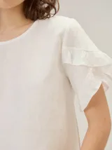 Blusa de lino color rosado, de corte recto y holgado, con cuello redondo y mangas cortas adornadas con volados.