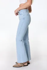 Jean azul claro de corte flare con aberturas en los tobillos y detalles rotos en las rodillas y muslos.