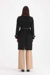 Piloto 7/8 de corte trench, color negro con detalles en beige en cuello, solapas y puños. Presenta cierre cruzado con botones, cinturón con hebilla y charreteras en los hombros.