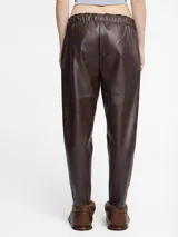 Pantalón de cuerina color negro con cintura elástica y cordón de ajuste. Presenta un corte tipo jogger con bolsillos laterales.