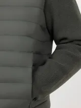 Chaqueta híbrida para hombre con frente acolchado de nylon y mangas de tejido de punto. Cuenta con cierre frontal, capucha y puños acanalados.