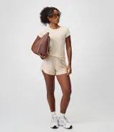 Bermuda deportiva Get Over de mujer, modelo runner en color beige, con cintura elástica, bajo redondeado y rayas laterales contrastantes.