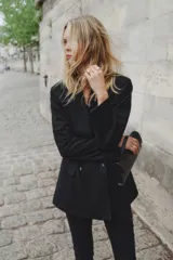 Blazer negro de doble botonadura con solapas de muesca, hombreras y bolsillos delanteros ribeteados con solapa.