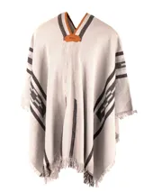 Poncho de tejido de punto con diseño geométrico en colores negro, rojo y beige, con terminaciones de flecos en el ruedo y escote en V.