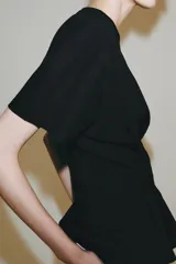 Camiseta de algodón con cuello redondo y manga corta. Presenta un diseño entallado con pinzas en la cintura y bajo recto.