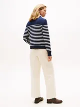 Sweater de punto fino en algodón, con diseño de rayas horizontales en azul marino y blanco. Presenta cuello redondo, mangas largas con puños acanalados y detalle de botones dorados en uno de los hombros.