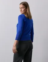 Cardigan blanco de tejido fino con abertura central y botones.