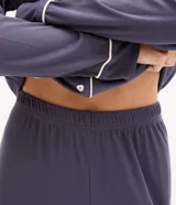 Pijama de dos piezas estilo americano en color azul grisáceo. La blusa es de manga larga con cuello solapa, cierre frontal de botones y detalle de bies en contraste. El pantalón es de corte recto con cintura elástica y detalle de bies en el ruedo.