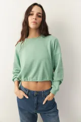 Buzo celeste cropped de manga larga con puños y cordones ajustables en la cintura.