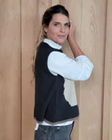 Chaleco tejido de punto con diseño abstracto en bloques de color marrón y turquesa, con cuello redondo y terminaciones acanaladas.