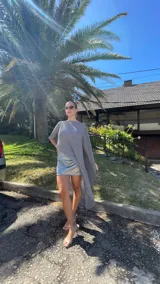 Vestido corto de dos piezas compuesto por una base strapless con frunces y acabado satinado, acompañada de una capa transparente desmontable de corte asimétrico.