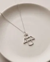 Collar de plata con cadena fina de eslabones y dije en forma de ángel con un corazón hueco en el centro.