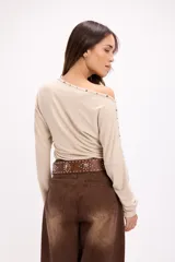 Cinto de cuero marrón con hebilla metálica grande de diseño circular y tachas decorativas a lo largo de la tira.