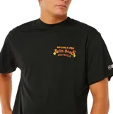 Remera de manga corta color negro con estampa pequeña en el pecho que dice Rip Curl Pro Bells Beach Australia en tonos cálidos.