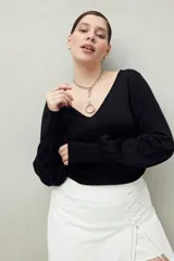 Top negro de tejido sutilmente metalizado, con escote en V y mangas abullonadas.