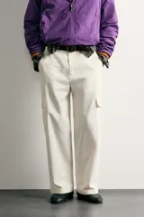 Pantalón cargo relaxed fit de color blanco, confeccionado en tejido de algodón. Presenta bolsillos de plastrón con solapa en las perneras y cierre frontal con cremallera y botón.