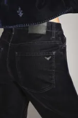 Pantalón de jean con acabado de terciopelo color azul marino, de tiro medio y corte sutilmente acampanado. Presenta cierre y botón frontal, con ruedo ancho como detalle.
