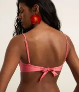 Top de bikini rosado con aro, modelo media taza, con tirantes finos ajustables y lazo en la espalda. Detalle de mini adornos de madera en el borde superior.