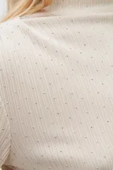 Blusa beige claro con cuello alto y mangas largas, con pequeños brillos.