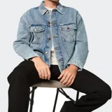 Campera de jean Wrangler en tono azul lavado, con cierre frontal de botones metálicos, cuello clásico y dos bolsillos frontales con solapa y detalle de costura en W.