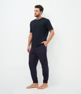 Pantalón de pijama tipo jogger para hombre, confeccionado en tejido plush suave y abrigado. Presenta un diseño estampado a cuadros, cintura elástica con cordón de ajuste y puños elásticos en los tobillos.