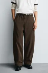 Pantalón de algodón color marrón oscuro, estilo balloon fit, con talle alto, cierre frontal y trabillas ajustables en los bajos. Presenta costuras verticales marcadas en el frente de cada pierna.