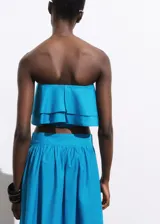 Top corto tipo palabra de honor, con diseño de volantes en capas y cierre de cremallera en la parte posterior.