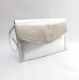 Sobre de fiesta plateado con formato tipo carta realizado en cuero metalizado. Tiene un bolsillo interior y un lazo para aferrarlo a la muñeca.