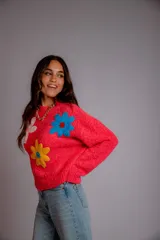 Buzo negro de tejido texturizado con apliques de flores de crochet en colores rosa pálido, amarillo y azul. Tiene cuello redondo y mangas largas.