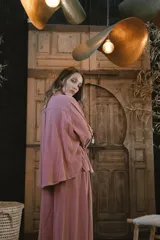 Camisa de lino negra con bordados dorados en forma de árbol o palmera estilizada. Presenta cuello camisero, botones frontales dorados y pliegues verticales en la parte inferior delantera.