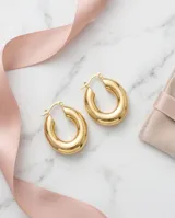 Aros tipo argolla gruesa de acero con baño de oro, diseño minimalista y acabado brillante.