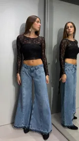 Jean de denim celeste de tiro bajo, con diseño flare de corte ancho en las piernas, costuras frontales destacadas y terminación desmechada en el ruedo.