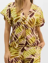 Conjunto de dos piezas confeccionado en mezcla de algodón y lino, con estampado abstracto en tonos verde y borravino. Incluye una blusa de manga corta con escote en V y cierre frontal con un botón, y un pantalón de tiro alto y pierna recta con bolsillos laterales.
