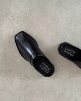 Zueco de cuero vacuno color negro, con diseño de punta cuadrada y suela plana.