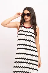 Vestido largo de punto con diseño de rayas en zigzag de color blanco y negro, sin mangas, con ribetes en tono bordó en el cuello y las sisas, y aberturas laterales en el bajo.