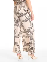 Conjunto de dos piezas compuesto por camisa de cuello solapa con escote en V y pantalón estilo palazzo de tiro alto. Ambas prendas presentan un estampado lineal abstracto en color negro sobre fondo beige. La camisa cuenta con mangas cortas ajustables mediante trabillas y un cordón trenzado negro para entallar la cintura. El pantalón posee cintura elastizada y bolsillos laterales.
