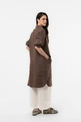Vestido camisero midi de lino color beige, de calce relajado, con cuello clásico, cierre frontal parcial con botones, mangas 3/4 regulables y bolsillos delanteros.