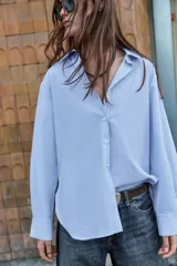 Camisa de manga larga con cuello solapa y cierre frontal de botones, confeccionada en tejido de algodón con estampado de cuadros vichy en tonos azul y blanco.
