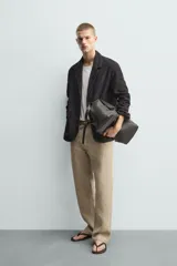 Blazer de corte relajado confeccionada en piel con acabado de ante. Presenta cuello con solapas de muesca, cierre frontal de dos botones, mangas largas y bolsillos de plastrón en la parte delantera. Destaca por sus costuras con efecto lavado que le otorgan un aspecto vintage.