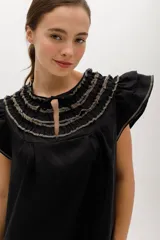 Vestido negro de lino, corte suelto, con cuello redondo con volados y mangas cortas con volados.