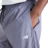 Pantalón New Balance Sport Legacy, diseño bicolor en tonos gris y azul marino, con cintura elástica ajustable mediante cordón y logo bordado en blanco.