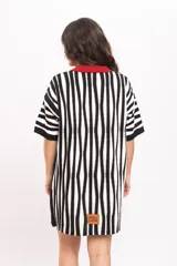 Vestido camisola corto de tejido fresco de algodón, con diseño de rayas verticales en blanco y negro. Presenta cuello polo, solapa y ribete central con botones en color rojo.