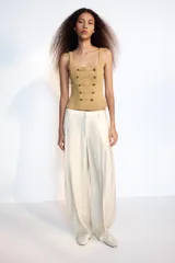 Top corsetero de color tostado con escote cuadrado, tirantes anchos y cierre de cremallera en la espalda. Cuenta con costuras marcadas y filas de botones metálicos dorados decorativos en el frente.