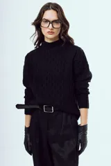 Sweater tejido negro de silueta relajada, con cuello alto y textura trenzada.