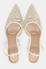 Zapato destalonado con tacón fino, color blanco. Capellada de mesh con bordados florales. Tira trasera elástica y punta fina. Tacón de 6 cm.