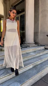 Vestido largo de red color blanco roto, sin mangas y con tajo lateral. Se usa sobre otra prenda interior.