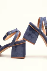 Sandalia de tacón cuadrado medio, confeccionada en terciopelo negro. Presenta un diseño de tiras cruzadas con nudo en la parte delantera y una tira ajustable con hebilla en el tobillo.